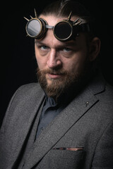Obraz premium charismatic man in a classic suit and steampunk goggles on a black background stylish Portrait
