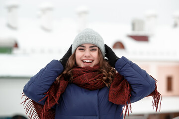 Portrait of a young happy woman enjoying winter wearing scarf and knitted hat.