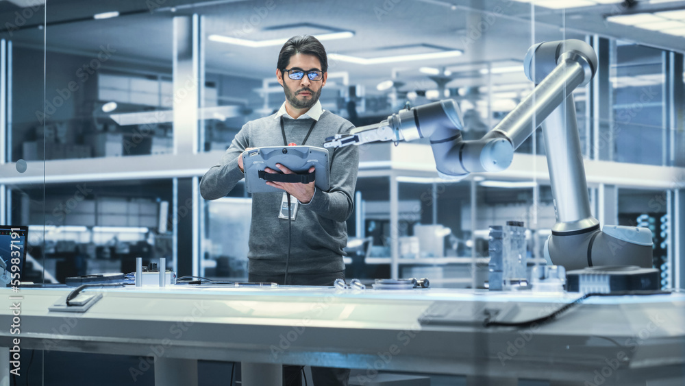 Poster Robotics Engineer Researching and Developing a Technological Robot Arm Project, Standing with Tablet Computer in Scientific Technology Lab. Young Male Working on an AI Robotic Arm.