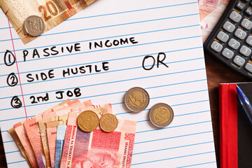Concept of ways to earn additional income. White marker board with south african currency, calculator and notebook. Ways to earn a second income options written on board