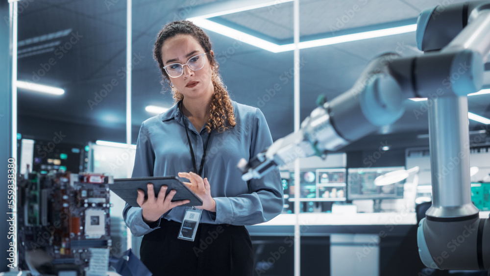 Fototapete Industrial Robotics Engineer Interacting with Robotic Arm During an Experiment in a High Tech Startup. Female Scientist Uses Tablet Computer to Manipulate and Program the Robot to Move a Microchip.