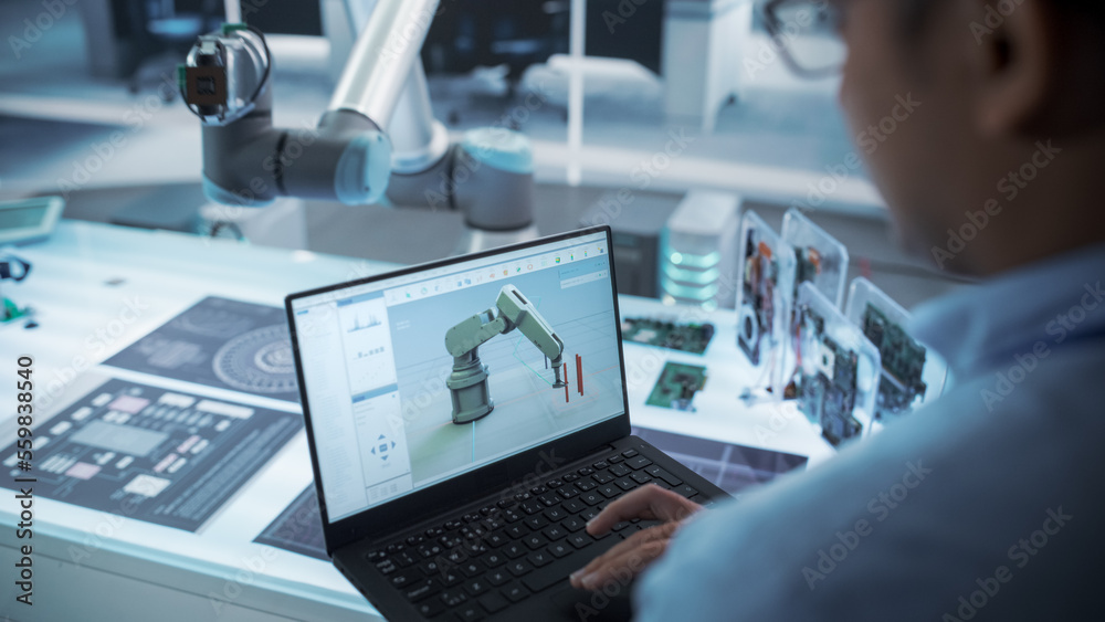 Fototapete Over the Shoulder Shot of a Robotics Engineer Using a Laptop Computer with a Software Operating the Robotic Arm. Robot Hand Holding a Microchip. Automation Startup Research and Development Office.
