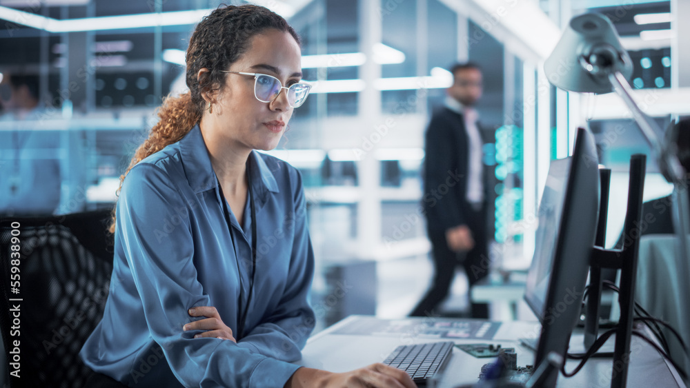 Poster Focused Multiethnic Female Industrial Engineer Developing 3D Model of a Circuit Motherboard on Computer CAD Software in a Startup Facility. Modern Technological Research and Development Center.