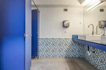 Gym toilet with blue partitions, porcelain sink and blue countertop to match the partitions