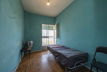 Shabby room painted ugly blue years ago with an individual gray metal folding bed