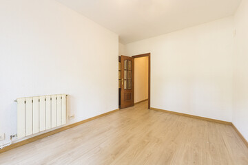 Fototapeta na wymiar Empty room with oak hardwood floors, matching skirting boards and varnished sapele wood access door with beveled glass