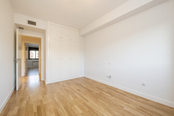 Empty living room with a three-door built-in wardrobe with a mezzanine with luggage compartments and air conditioning through ducts installed in the false ceiling