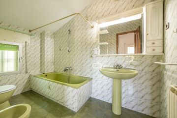 Bathroom with a wall covered in green vintage tile, a bathtub of the same color, a sink with a base and a white cabinet with spotlights and an integrated mirror