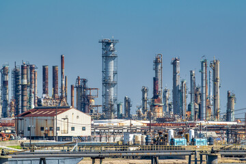 Oil refinery industry view details of pipes with valves in a large refinery isolated on blue sky