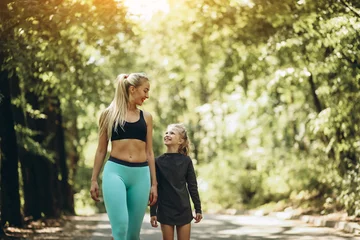 Tuinposter Mother with daughter jogging in park © Petro
