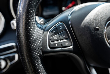 Leather multifunction steering wheel in a luxury car, visible buttons for navigation in the on-board computer, on the left.