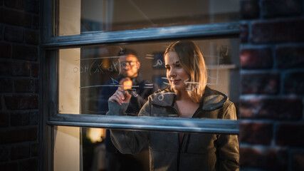 White Young Female Explaining a Math Equation on a Window at Home to a Male Friend by Using Erasable Glass Markers. Two Multiethnic Future Engineers Studying Together. University Student Life
