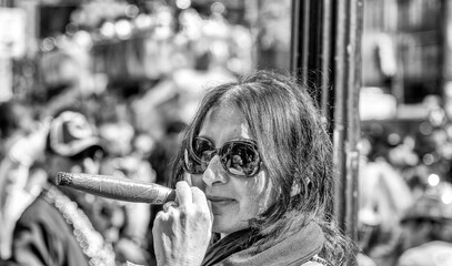Happy woman at New Orleans carnival on Mardi gras major event pretends to smoke a toy cigar