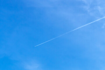 Jet aircraft flying on the high altitude against the backdrop of a clear blue sky. Airplane with two condensation trail on clouds and sky. View of airplane trace among the clouds and clear blue sky.