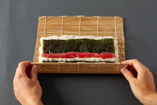 Crop person rolling maki sushi