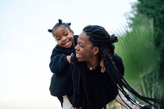 Happy black mother giving piggyback ride to daughter