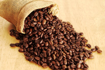 Sack of coffee beans on wooden background