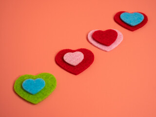 Heart of different colors on a pink background.