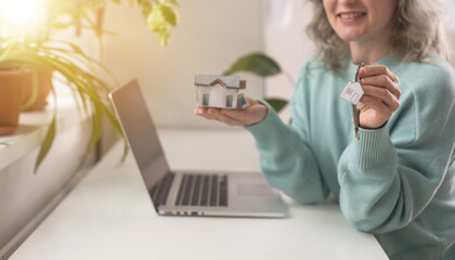 Woman holding white house model and house key in hand.Mortgage loan approval home loan and...