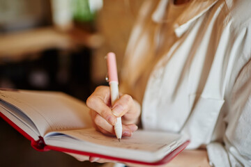 Faceless woman taking notes in notebook
