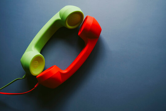 Red and green telephone handsets placed on table