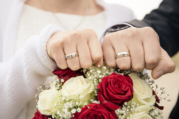 goldene Eheringe von Braut und Bräutigam klassisch mit roten und weissen Rosen - 559847787