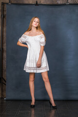 Portrait of a young beautiful blonde model in white dress