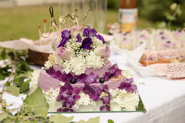 lila Hochzeitstorte auf sweet table mit frischen Blumen