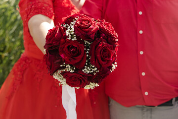 Brautpaar hält klassischen Brautstrauss mit roten Rosen - 559851711