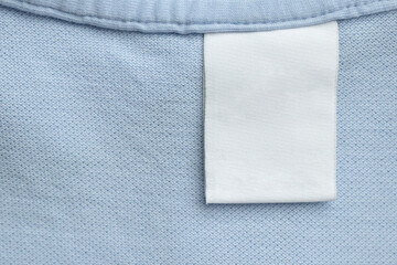White blank laundry care clothes label on blue shirt fabric background