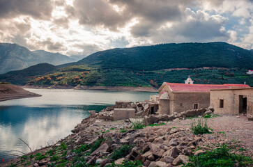 Fototapeta na wymiar The artificial dam of Aposelemi and the abandoned sunken village of Sfendili which is sinking in an effort, the local authorities to face the drought.