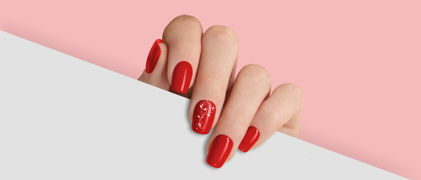 Woman's hand holding white paper. Fashionable red nail design