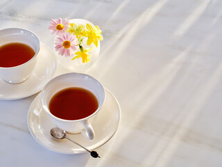 窓越しの午後の光と紅茶と春の小花