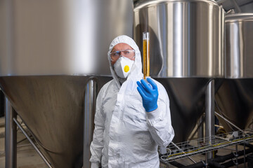 Fototapeta na wymiar Brewery technologist holding a glass vessel with yellow liquid