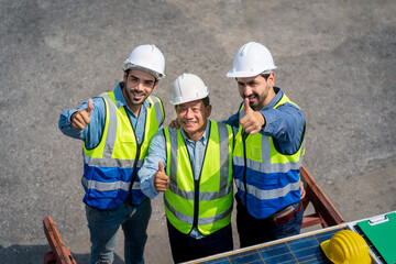 Portrait of Engineer or foreman team pointing up the future  with cargo container background at sunset. Logistics global import or export shipping industrial concept.