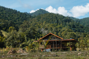 Obraz premium House in Northern Thailand countryside with green hills and tropical forest in the background