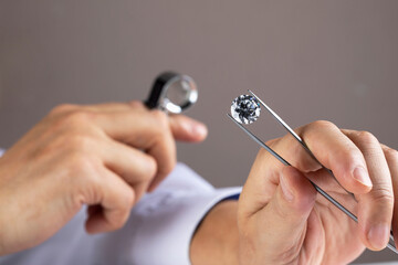 Close up of diamond expert's hand at workplace evaluating gemstones polished diamonds. High quality photo