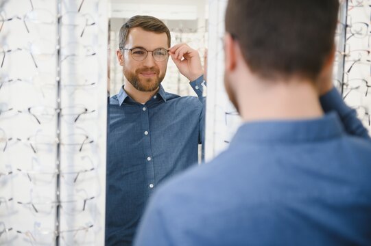 Shot of a handsome bearded man trying on new glasses at the eyewear store.Man buying glasses.Health, eyesight, vision, fashion, shopping
