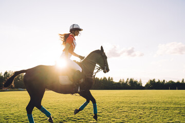 Young polo player in equipment riding mare on field