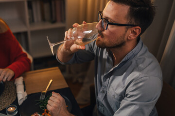 Side view of a man having a sip of white wine