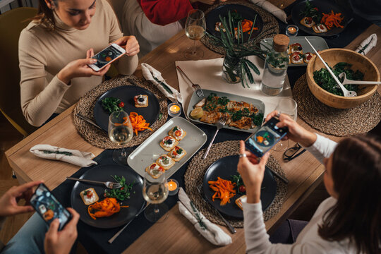 View from above of people taking pictures of their dinner plates using smart phones