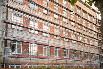 Restoration of a Soviet-era building. Restoration of the brick building. Scaffolding in front of brick house.