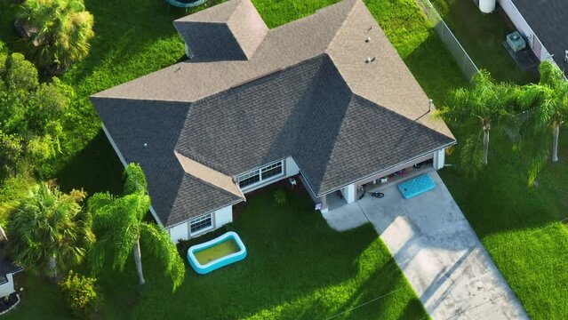 Aerial view of typical contemporary american private house with roof top covered with asphalt shingles and green lawn on yard