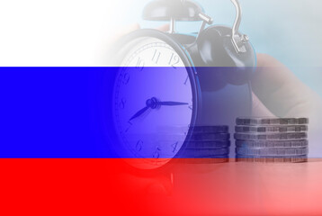 alarm clock on the background of the Russian flag and coins.