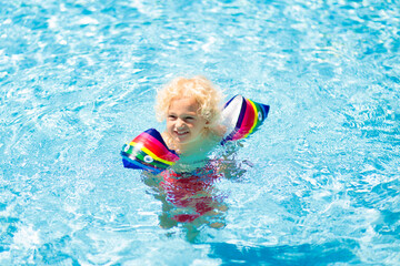 Fototapeta na wymiar Child in swimming pool. Kid with float armbands.