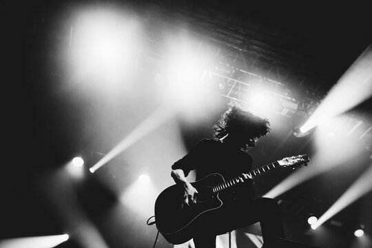 Silhouette of a guitar player. Guitarists perform on a concert stage. Dark background, smoke, concert spotlights.