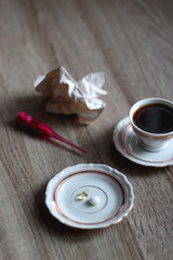 Cup of tea, pills, pink thermometer and used tissue on the table. Cold and flu concept. Selective focus.