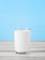 The glass full of milk on wooden table. Glass of fresh white milk on blue background in the kitchen.