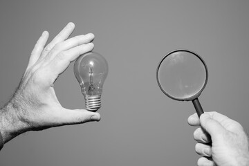 man is holding a light bulb and magnifying glass
