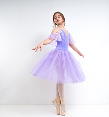 Naklejka premium Young ballerina in a purple dress on a white background.